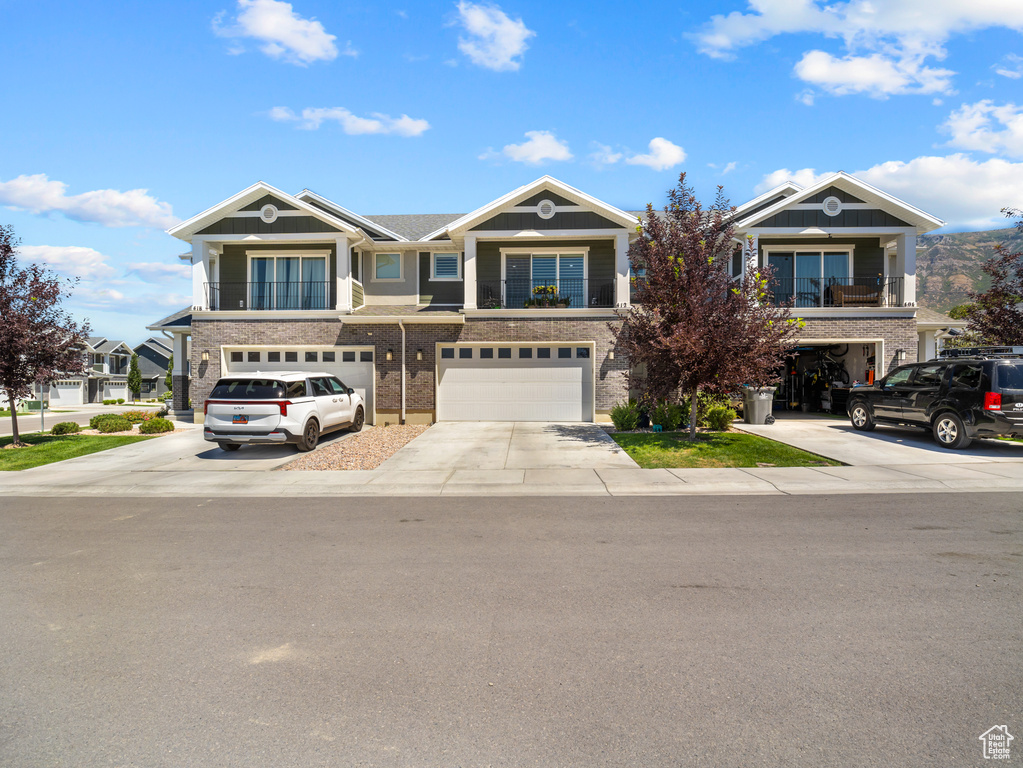 View of front of property with driveway, a garage, and a balcony