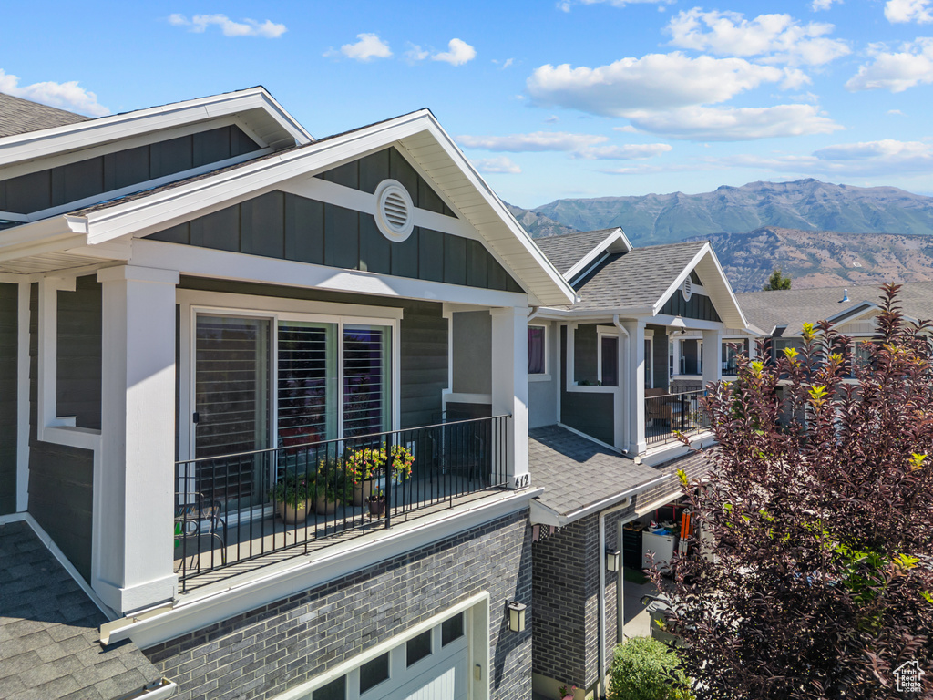 View of home\\\'s exterior with roof with shingles, board and batten siding, a mountain view, and brick siding