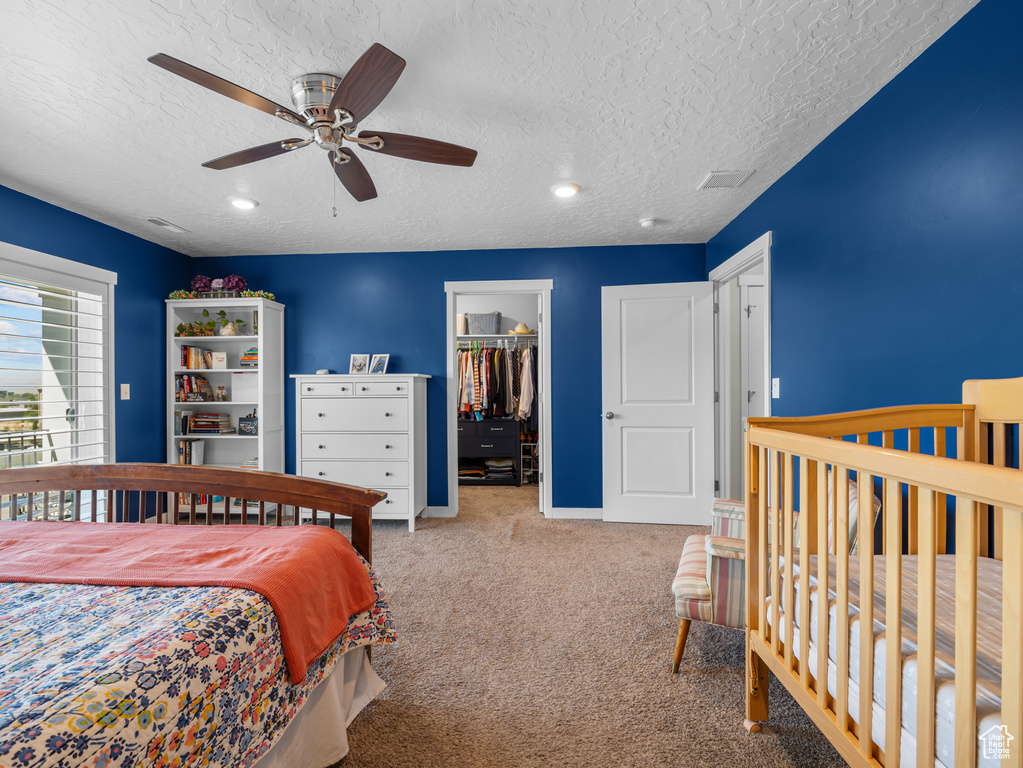 Bedroom featuring carpet, a textured ceiling, a walk in closet, recessed lighting, and a ceiling fan