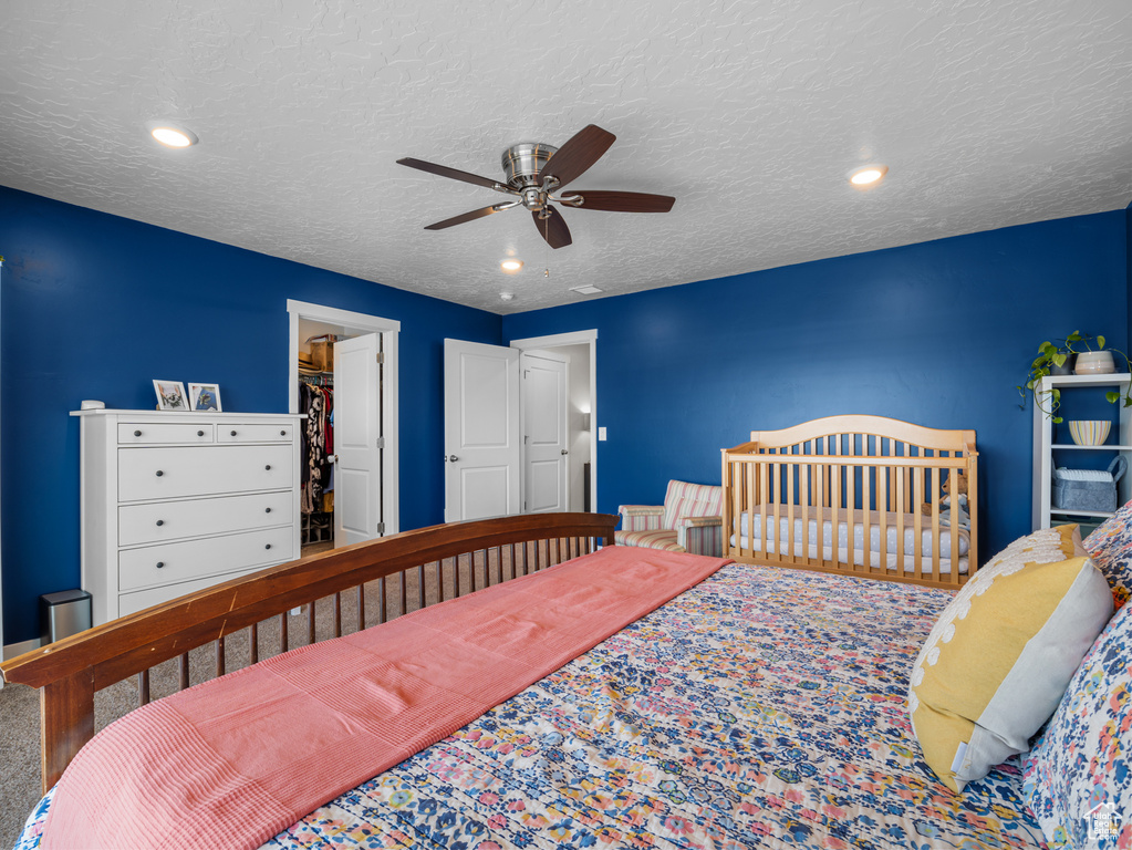 Bedroom with a ceiling fan, a walk in closet, a textured ceiling, and recessed lighting