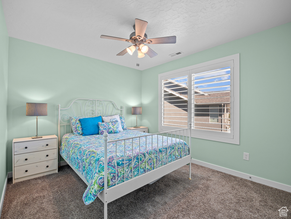 Bedroom featuring carpet floors, ceiling fan, and a textured ceiling