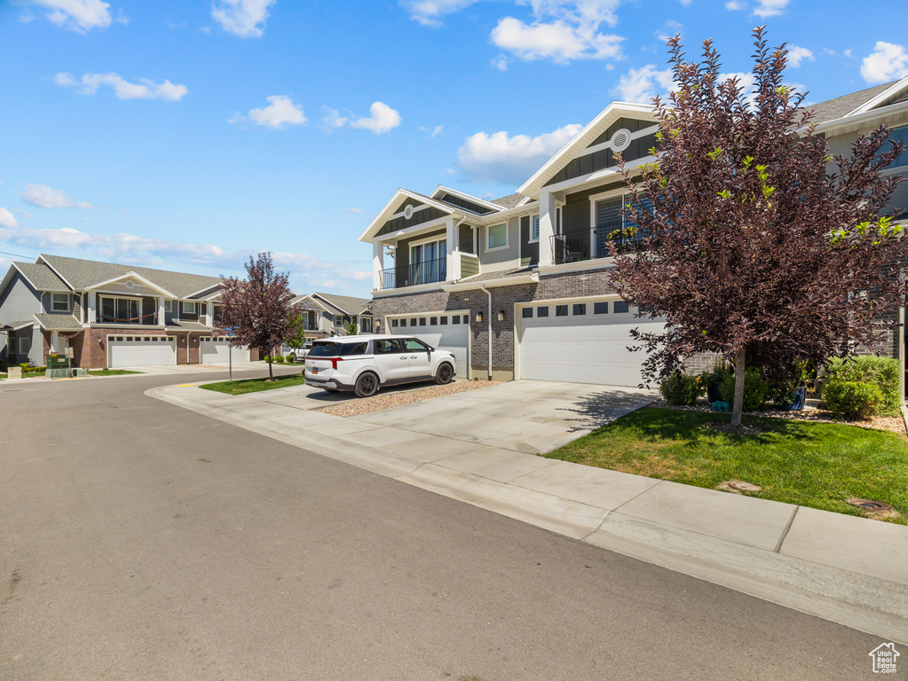 Craftsman-style home with driveway, a garage, a residential view, board and batten siding, and brick siding