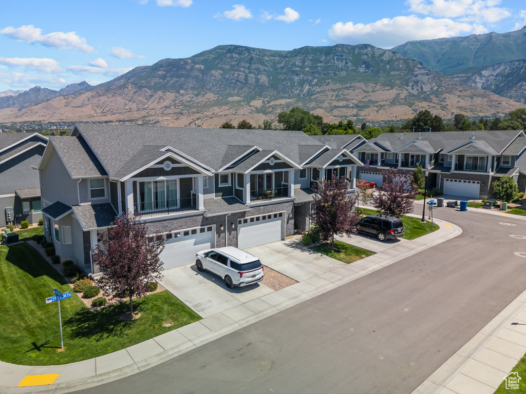 View of front facade featuring stone siding, driveway, an attached garage, a residential view, and a mountain view