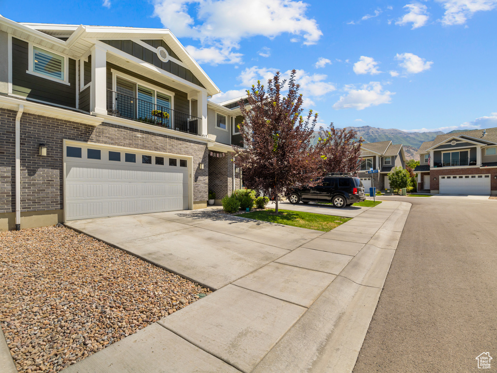 View of front facade featuring driveway, a garage, a mountain view, board and batten siding, and brick siding