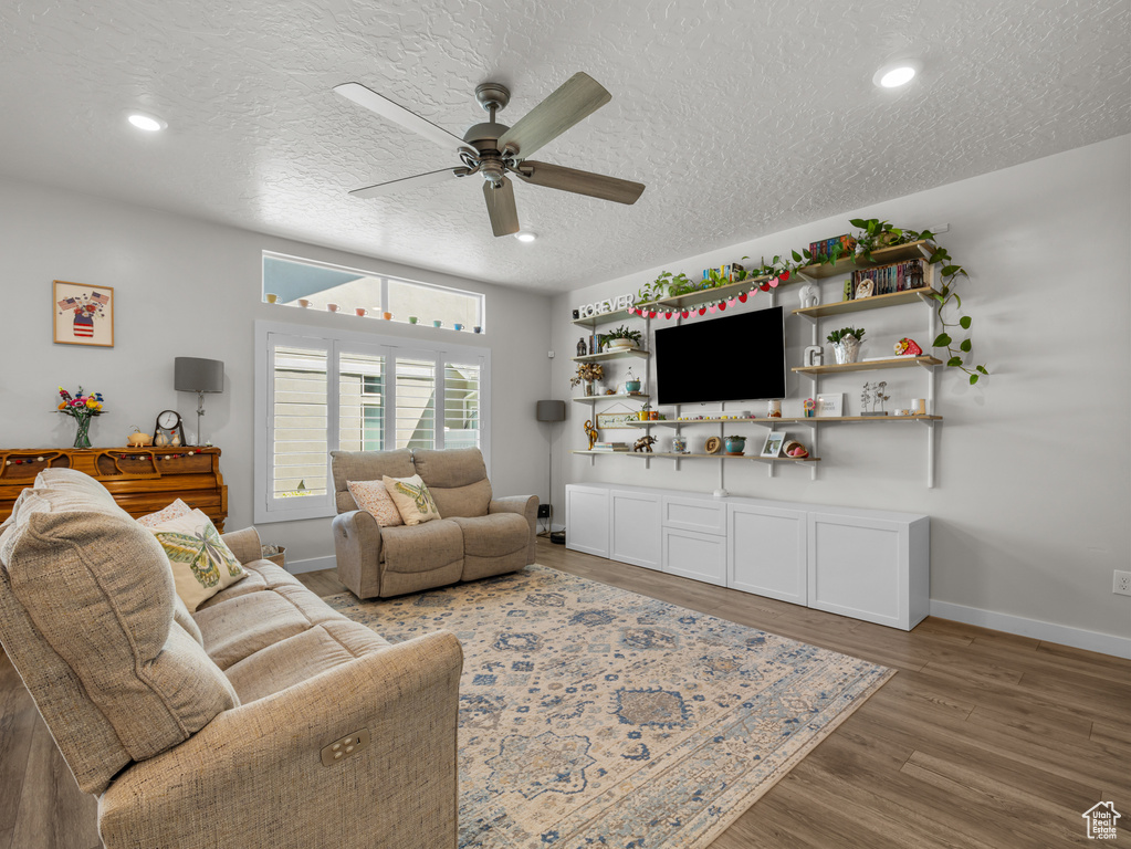 Living room featuring a ceiling fan, a textured ceiling, wood finished floors, and recessed lighting