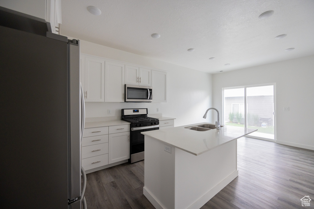 Kitchen with stainless steel appliances, dark wood-style floors, white cabinets, and light countertops