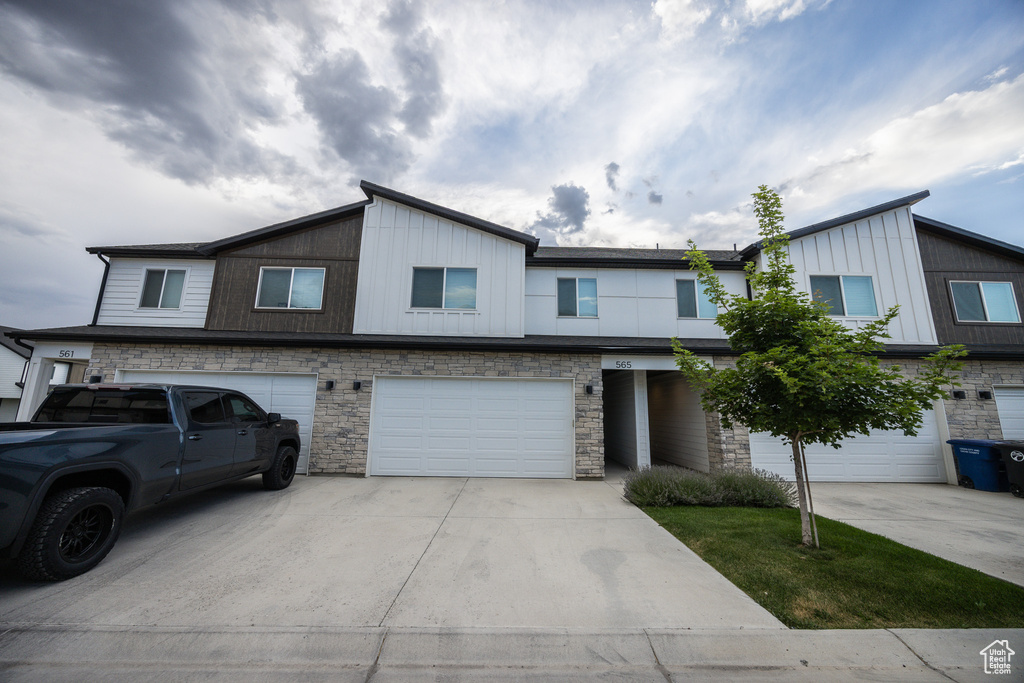 View of front of property with driveway, a garage, and stone siding
