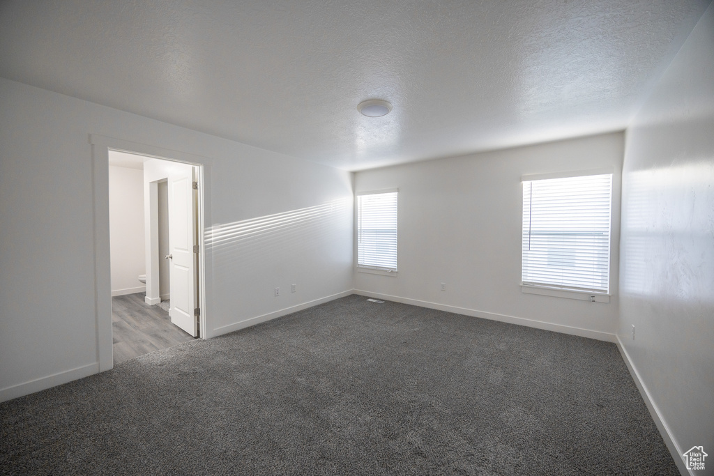 Unfurnished room featuring dark colored carpet and a textured ceiling