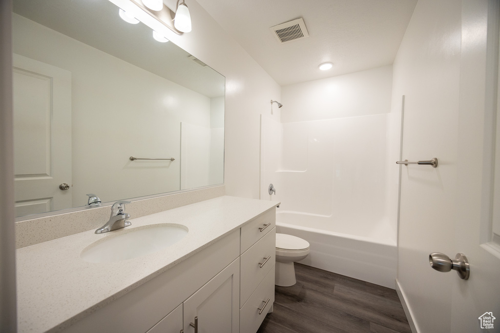 Bathroom with vanity, wood finished floors, and washtub / shower combination
