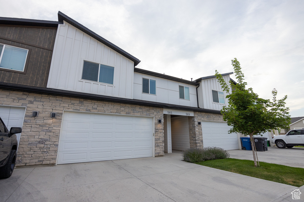 View of front of home with a garage, board and batten siding, concrete driveway, and stone siding