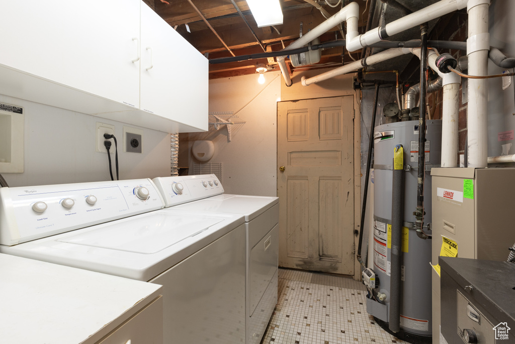 Washroom featuring washing machine and clothes dryer, cabinet space, water heater, and heating unit