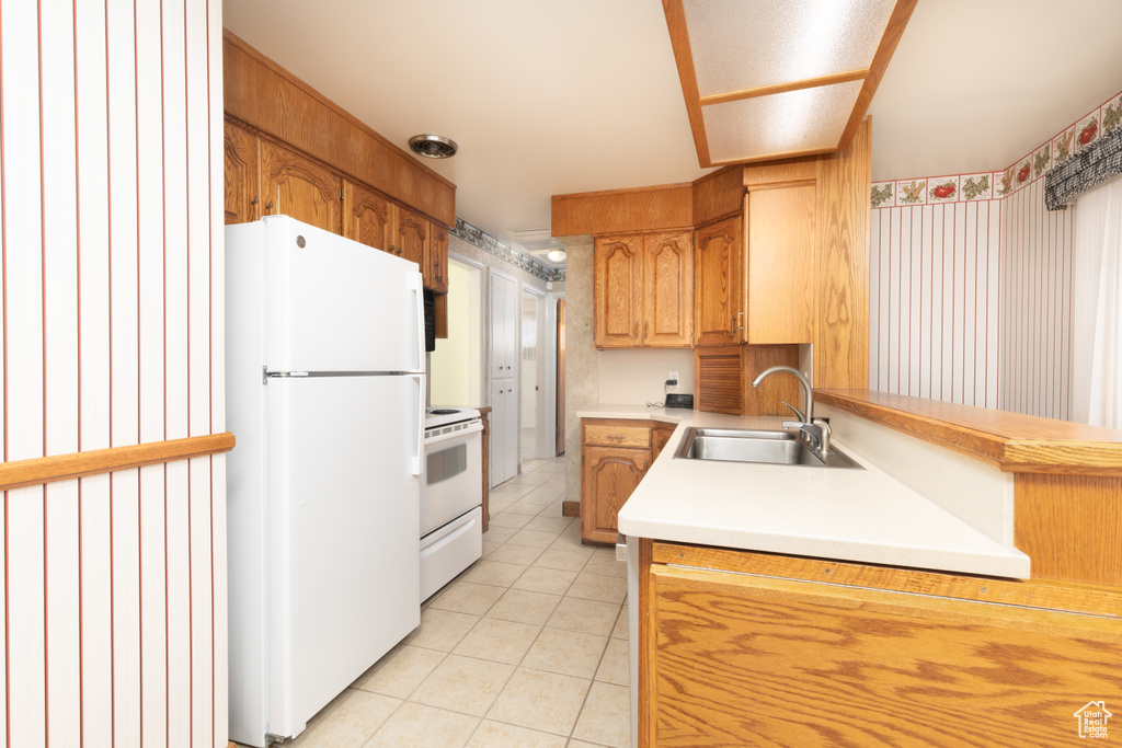 Kitchen with white appliances, light tile patterned floors, and light countertops