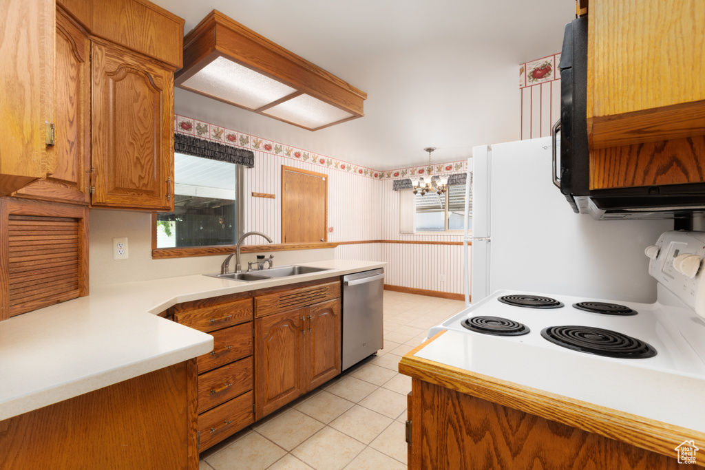 Kitchen featuring brown cabinets, white range with electric cooktop, light countertops, dishwasher, and a chandelier