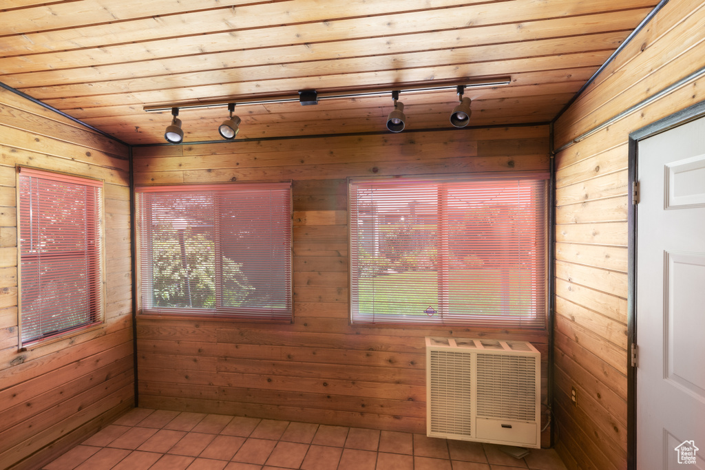 Unfurnished sunroom with rail lighting, healthy amount of natural light, and heating unit