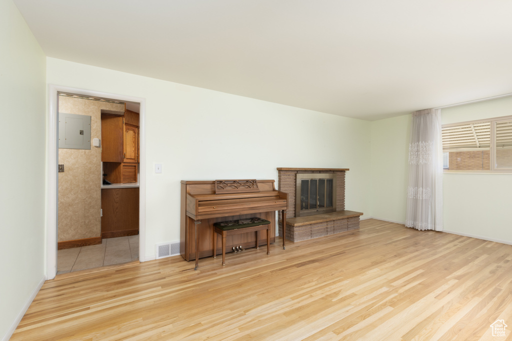 Living area with wood finished floors, electric panel, and a brick fireplace