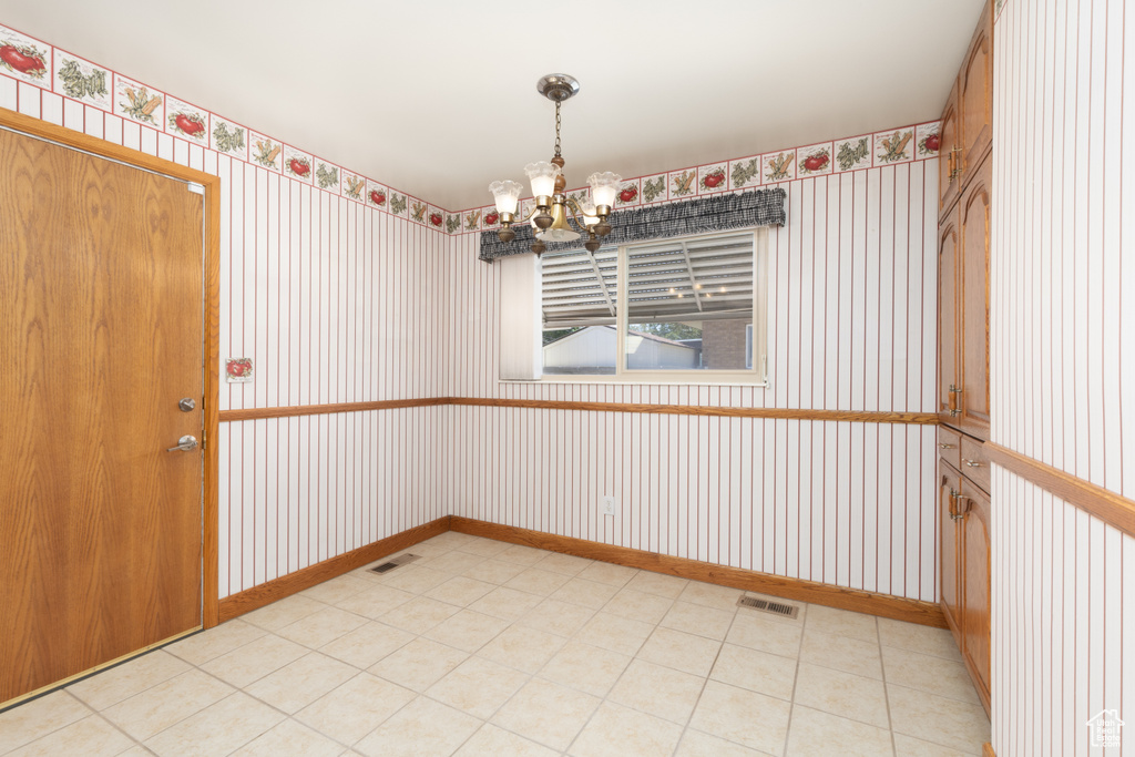 Spare room featuring wallpapered walls, a chandelier, and light flooring