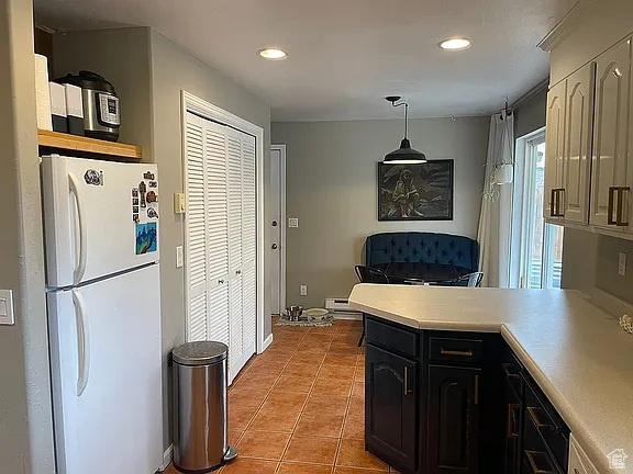 Kitchen featuring freestanding refrigerator, light tile patterned floors, light countertops, a peninsula, and recessed lighting