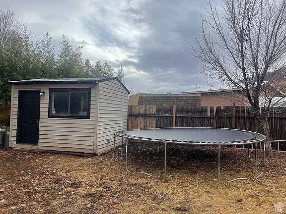 Fenced backyard with a trampoline and a storage unit