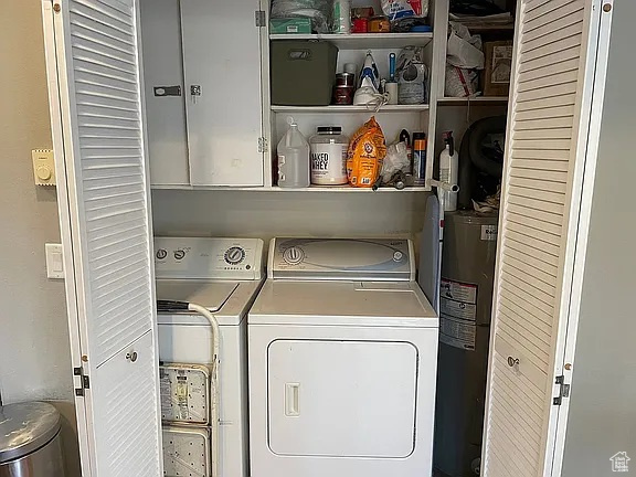 Laundry area with separate washer and dryer, cabinet space, and water heater