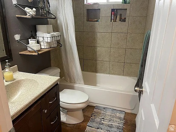 Full bathroom with vanity, shower / tub combo with curtain, and tile patterned floors