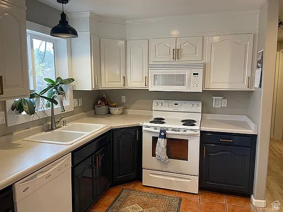 Kitchen with white appliances, white cabinetry, light countertops, and decorative light fixtures