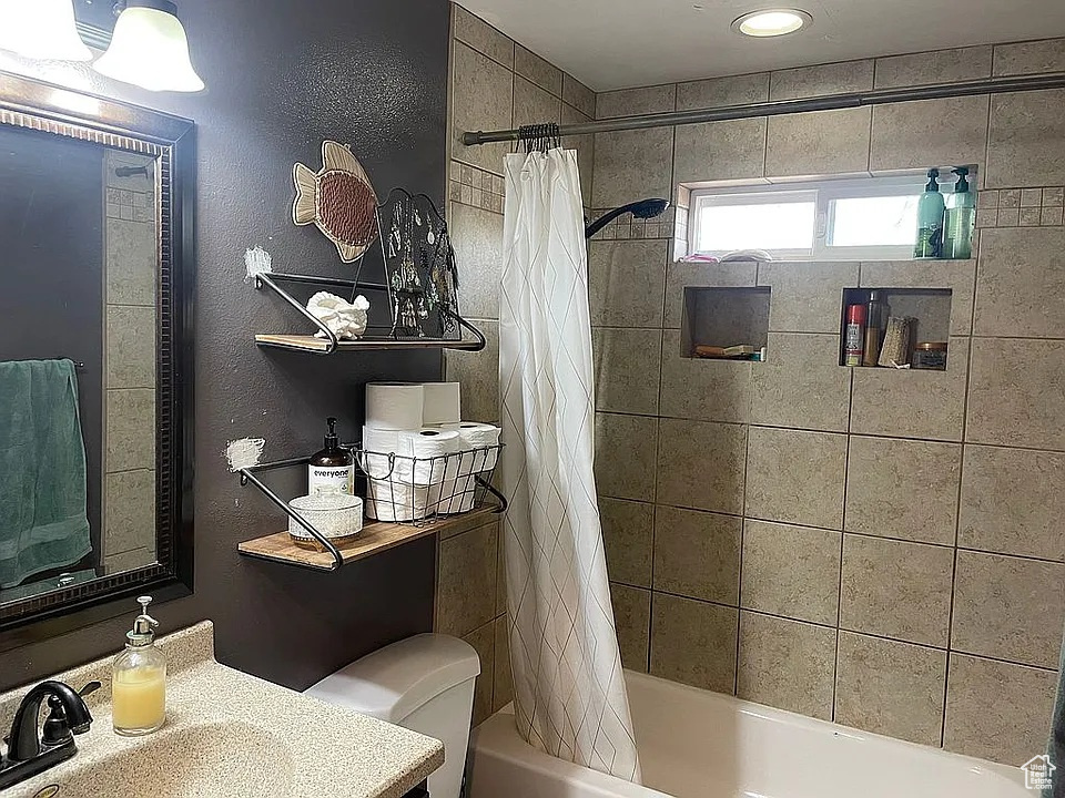 Bathroom featuring shower / bathtub combination with curtain and vanity