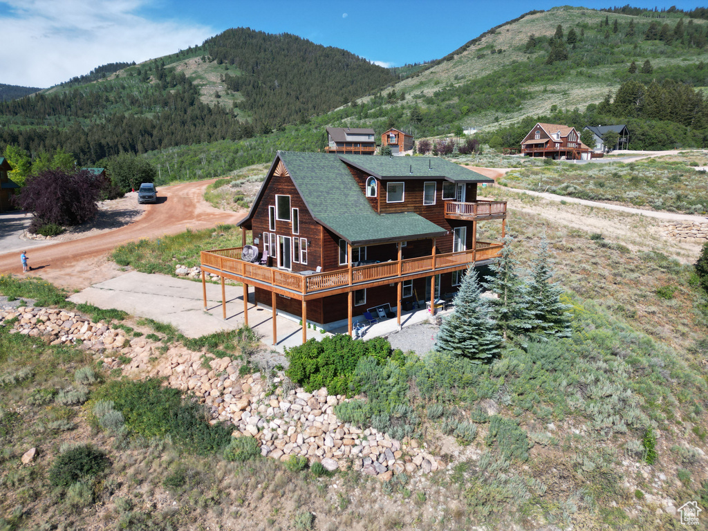Rear view of property with a deck with mountain view, a balcony, and roof with shingles