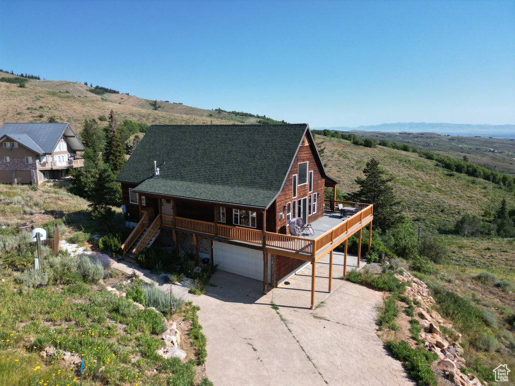 View of front of property with an attached garage, driveway, stairway, a shingled roof, and a deck