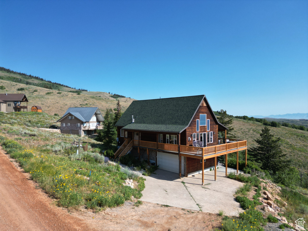 View of front facade with driveway, an attached garage, stairs, and a wooden deck