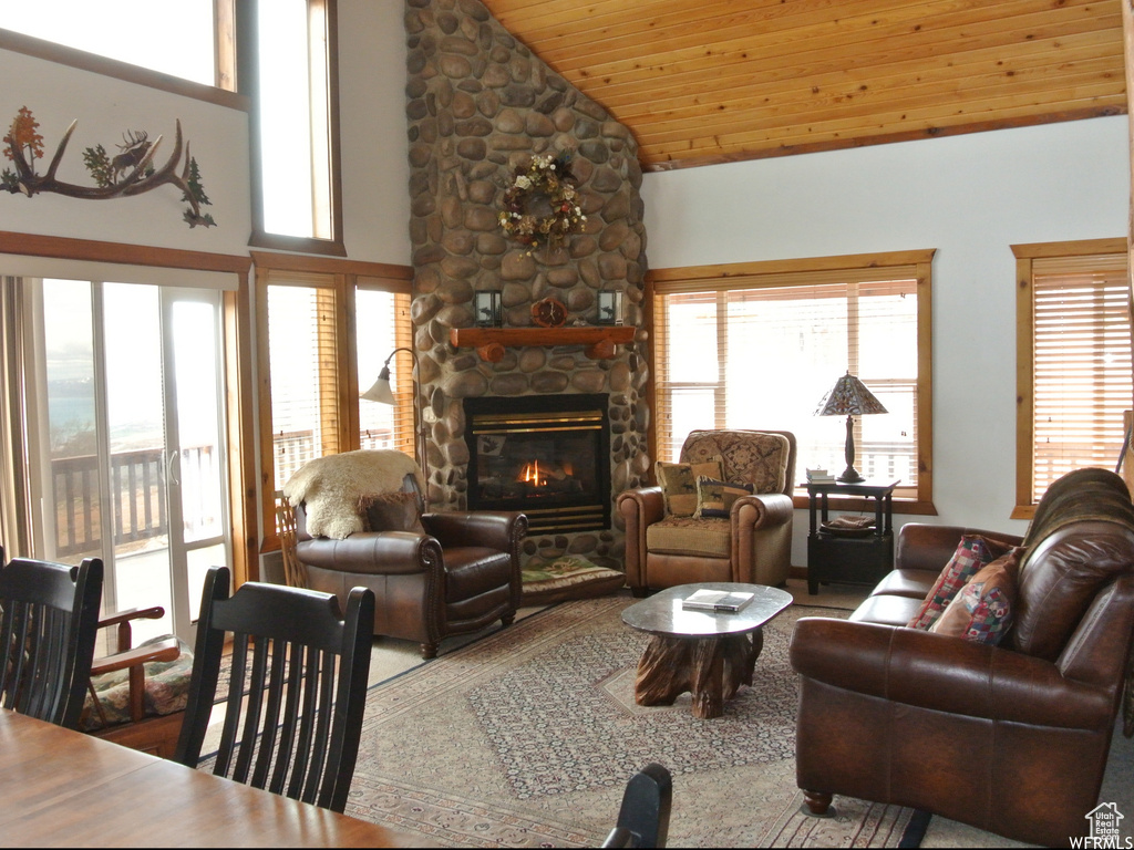 Living room with a stone fireplace, wooden ceiling, and high vaulted ceiling