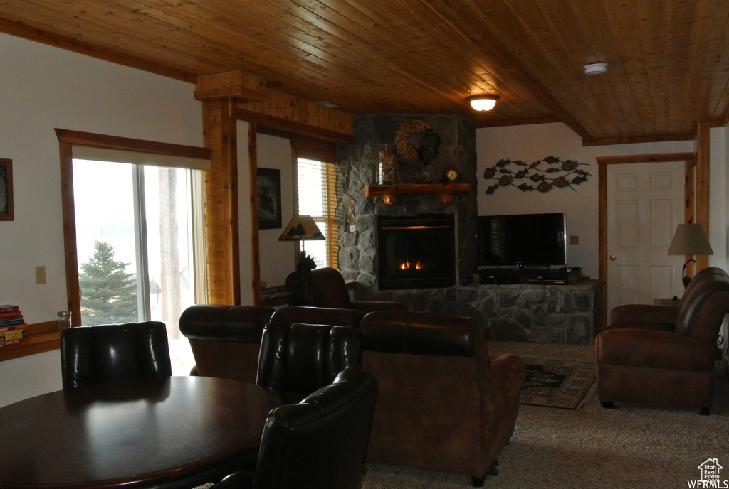 Carpeted living area with wood ceiling and a stone fireplace