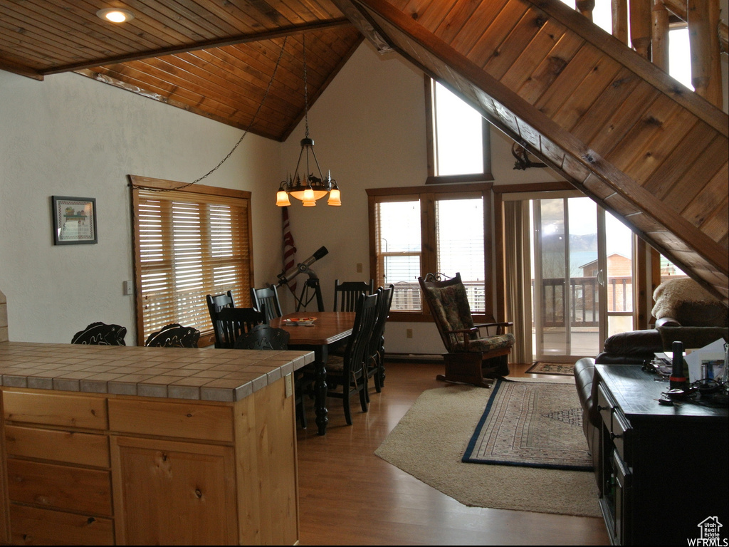 Kitchen with a wood ceiling with exposed beams, tile countertops, light wood-style floors, high vaulted ceiling, and hanging light fixtures