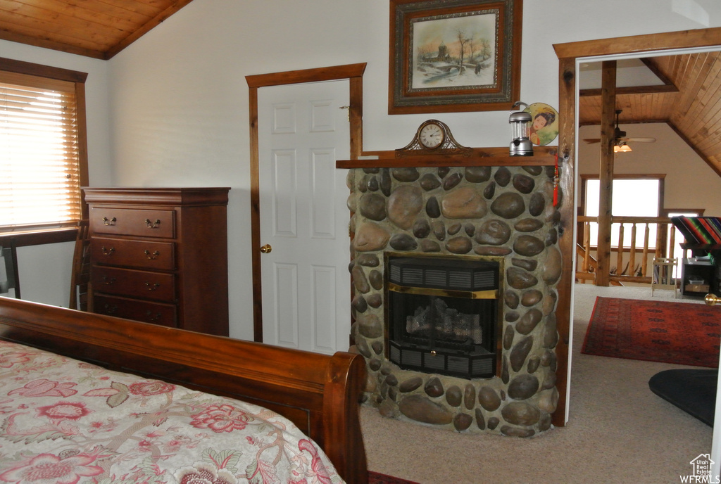 Carpeted bedroom with lofted ceiling, wood ceiling, and a fireplace