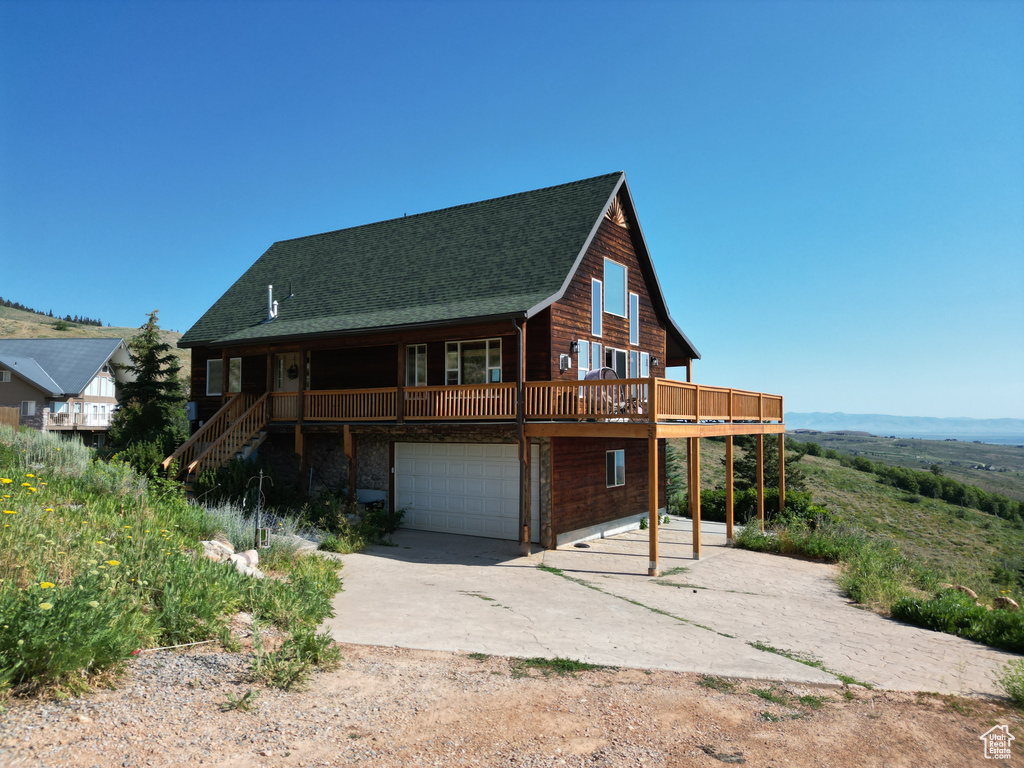 View of front of home with concrete driveway, a garage, roof with shingles, and stairs