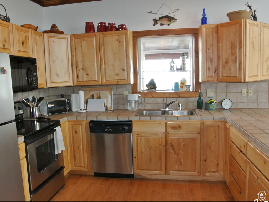 Kitchen with tile counters, stainless steel appliances, and light brown cabinets