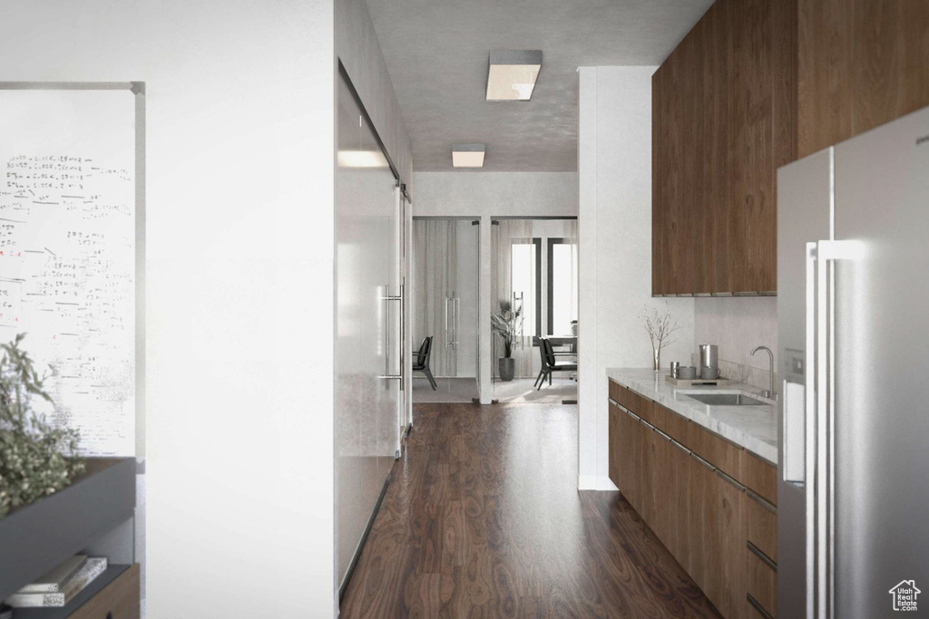Kitchen with stainless steel refrigerator with ice dispenser, dark wood finished floors, modern cabinets, light countertops, and built in refrigerator