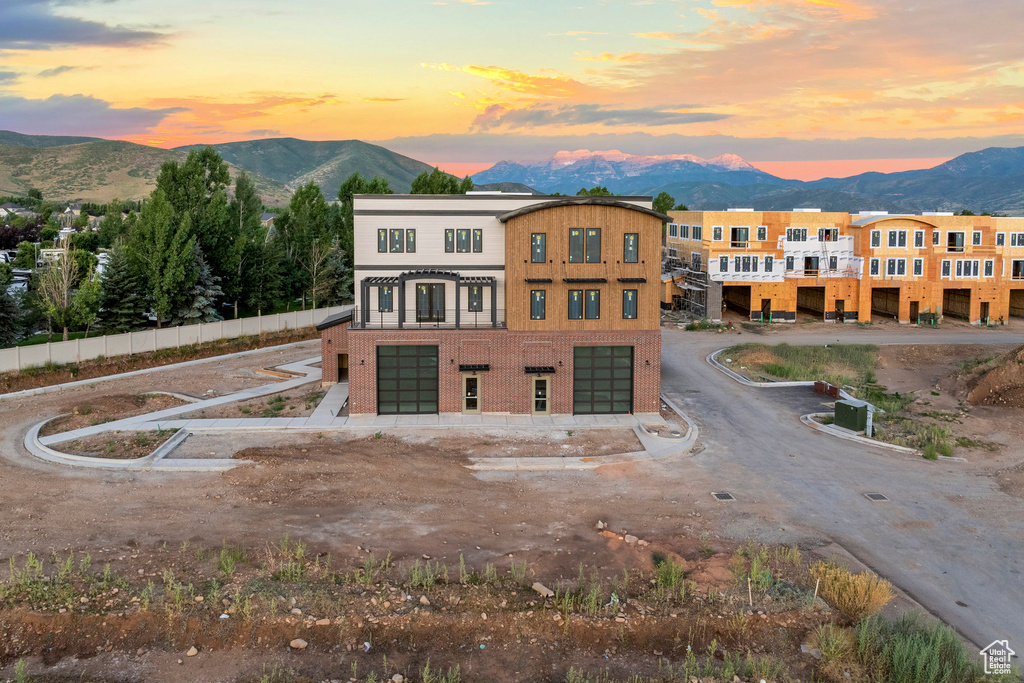 View of front of home with a garage, a mountain view, brick siding, and driveway