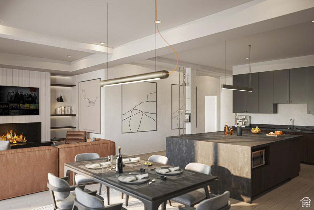 Dining area featuring light wood-type flooring, a warm lit fireplace, and recessed lighting