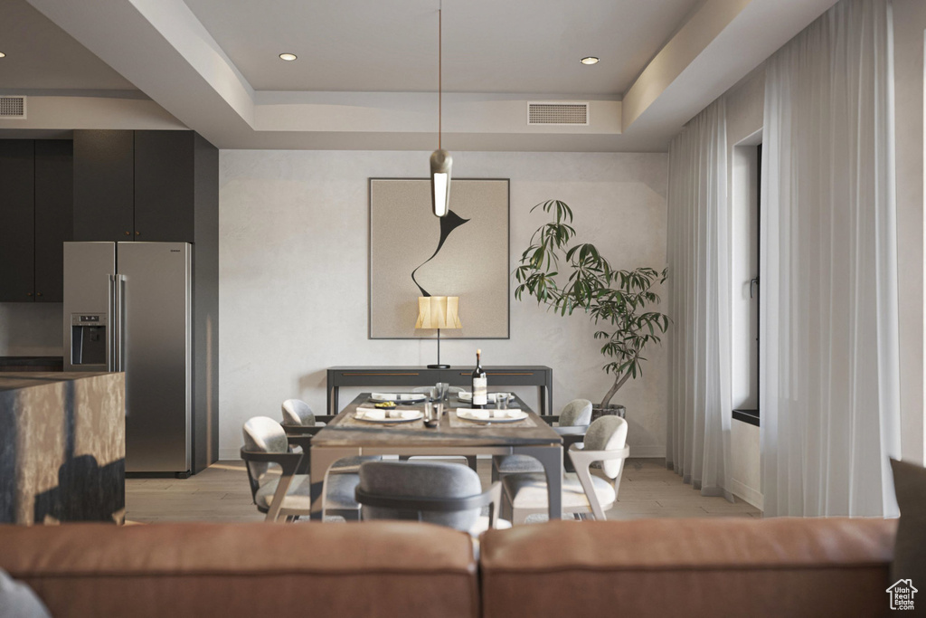 Dining room with light wood-style floors and a tray ceiling