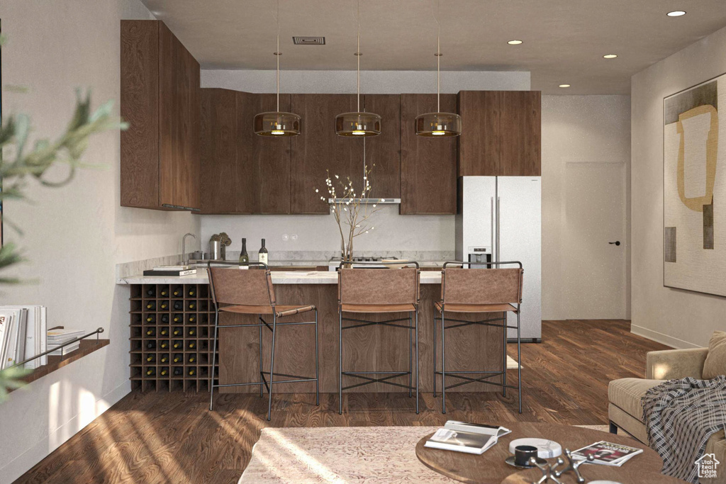 Kitchen with freestanding refrigerator, light countertops, dark brown cabinetry, a kitchen breakfast bar, and dark wood finished floors
