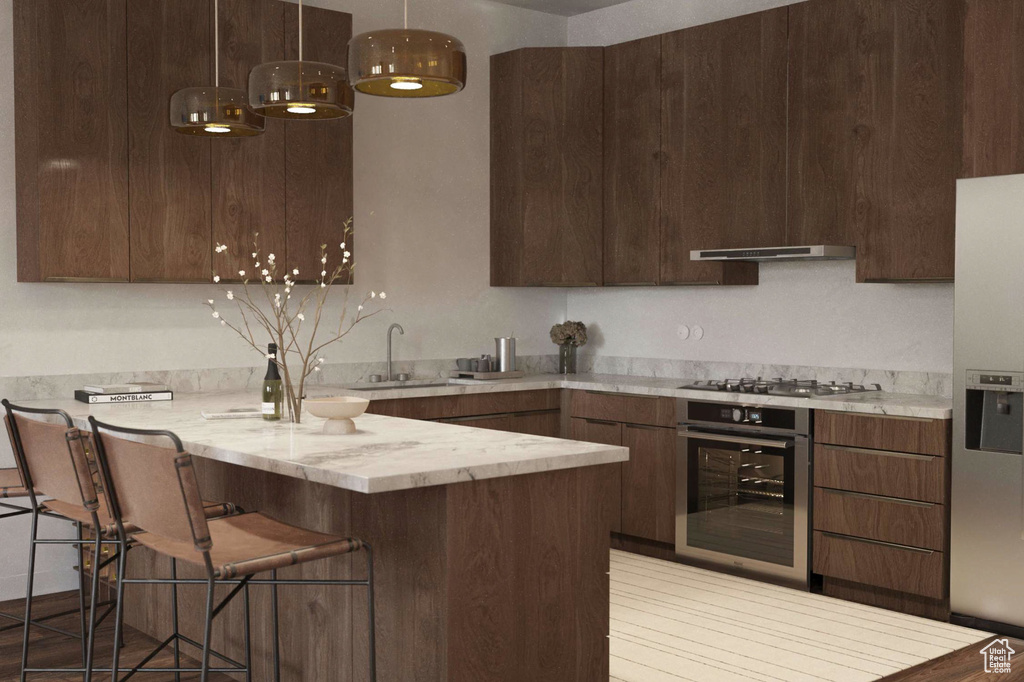 Kitchen featuring appliances with stainless steel finishes, a peninsula, a kitchen breakfast bar, modern cabinets, and pendant lighting