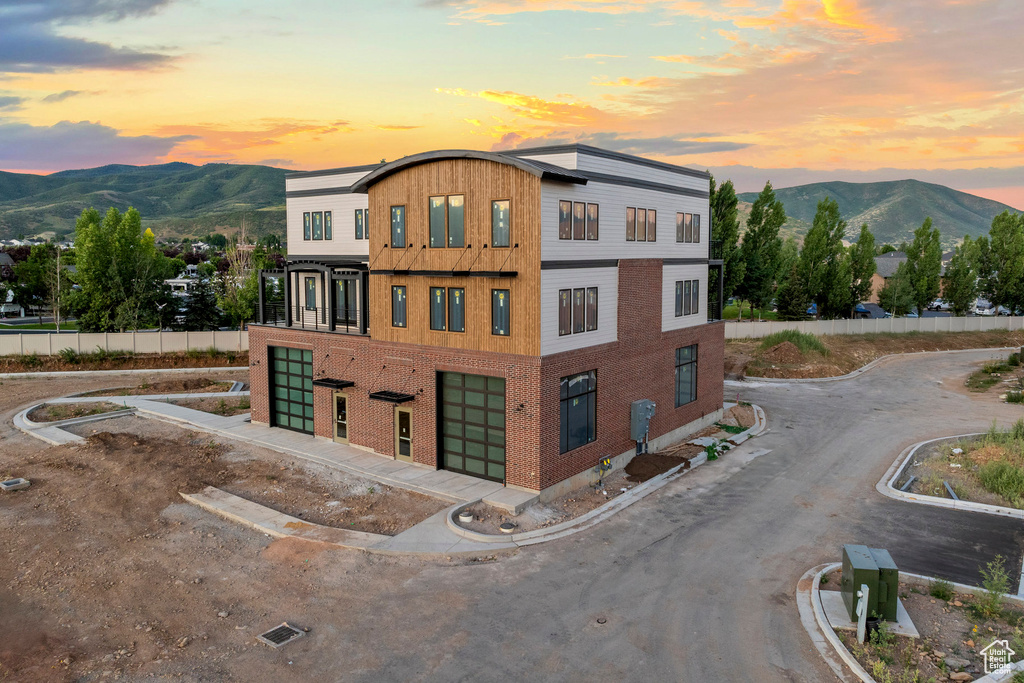 Property at dusk featuring an attached garage, a mountain view, and driveway