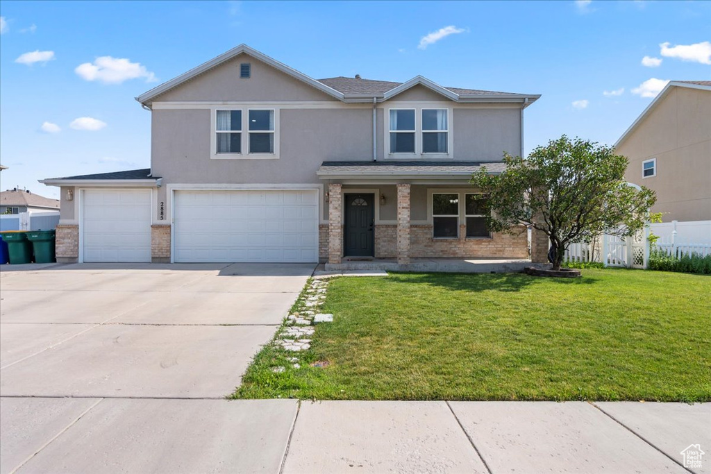View of front of home with concrete driveway, an attached garage, stucco siding, a front yard, and covered porch
