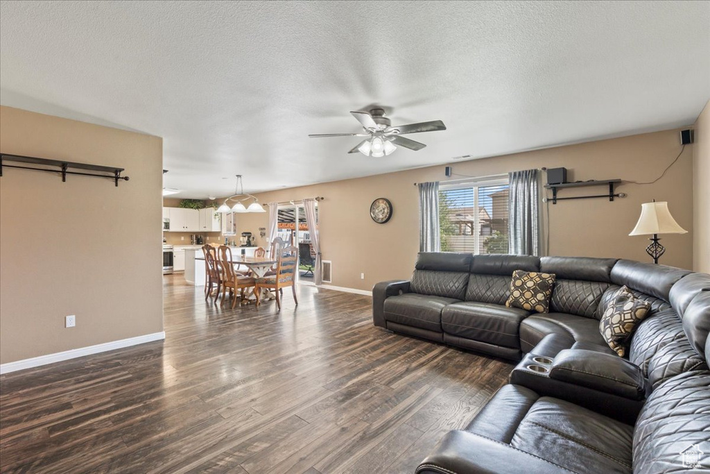 Living room featuring a ceiling fan, dark wood-type flooring, and a textured ceiling