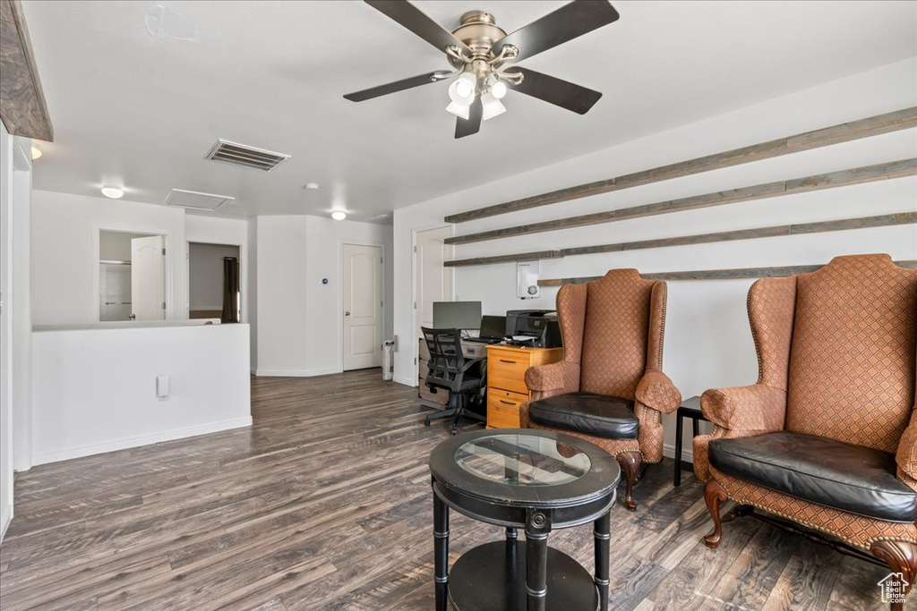 Sitting room with wood finished floors, a desk, and ceiling fan