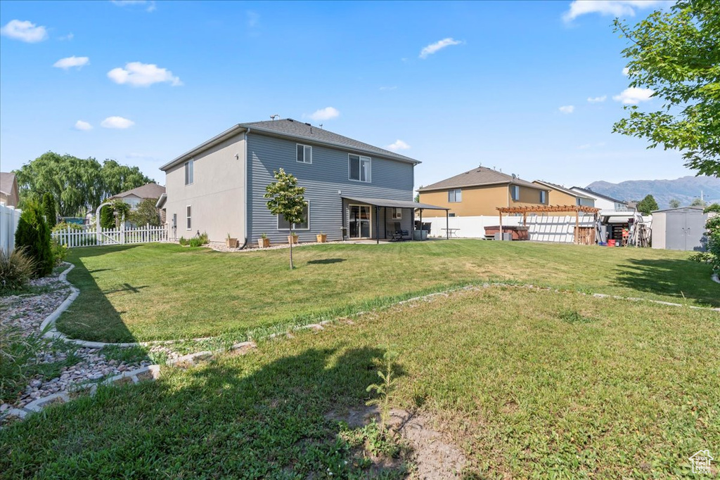 Fenced backyard featuring a storage unit and a patio area