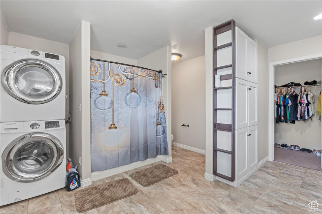 Full bath with estacked washer and dryer, a shower with curtain, and a walk in closet