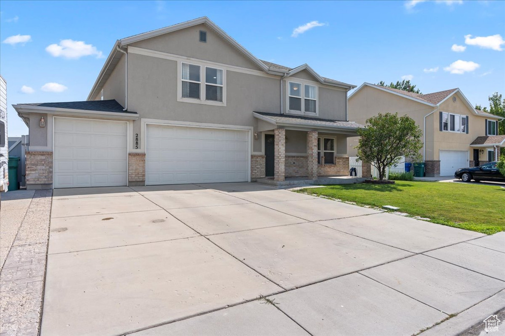 View of front facade with stucco siding, a front yard, an attached garage, and concrete driveway