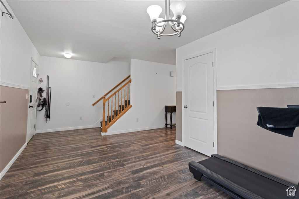 Exercise room with dark wood-type flooring and a chandelier