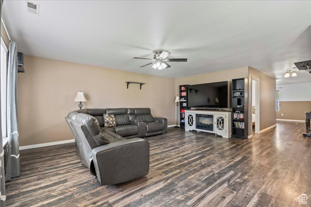 Living area featuring a ceiling fan and dark wood-style flooring
